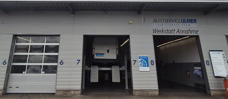 Werkstattannahme von Autoservice Ulmer: geöffnete Hallentore mit den Nummern 6, 7 und 8 und dem Schriftzug Werkstatt Annahme